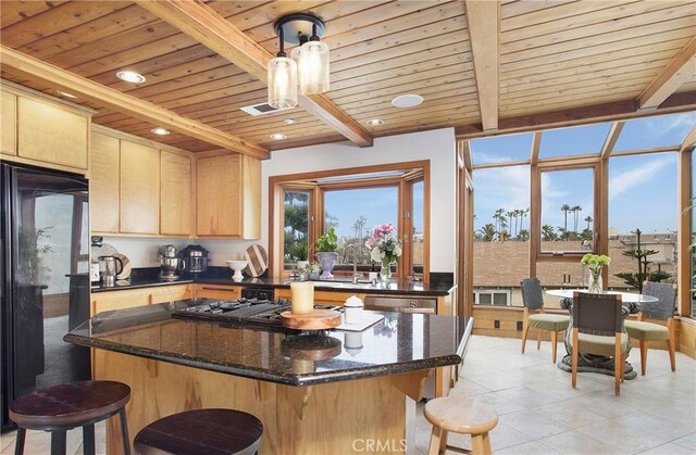 kitchen with light brown cabinetry, beam ceiling, a kitchen island, and light tile floors