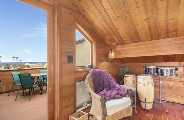 sitting room with lofted ceiling, wooden ceiling, and wood walls