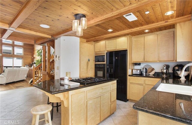 kitchen featuring beam ceiling, light hardwood / wood-style flooring, light brown cabinetry, and black appliances