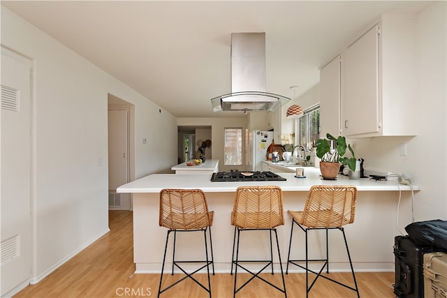 kitchen with island exhaust hood, kitchen peninsula, and light wood-type flooring