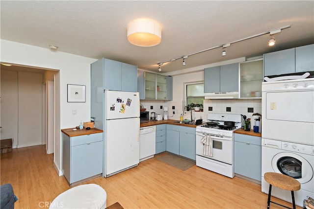 kitchen with light hardwood / wood-style floors, stacked washer / drying machine, tasteful backsplash, white appliances, and blue cabinetry