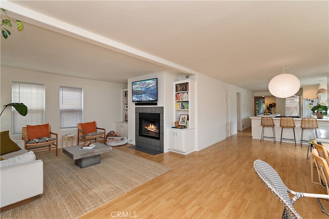 living room with a textured ceiling, hardwood / wood-style floors, and a tile fireplace