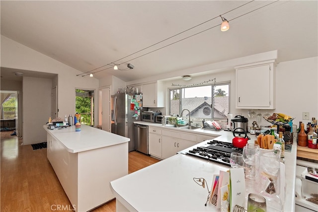 kitchen with light wood-type flooring, white cabinets, vaulted ceiling, kitchen peninsula, and stainless steel appliances