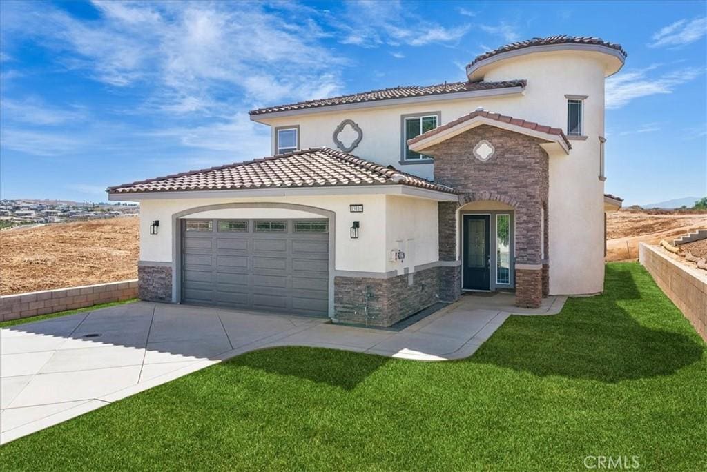 mediterranean / spanish home with a garage and a front lawn