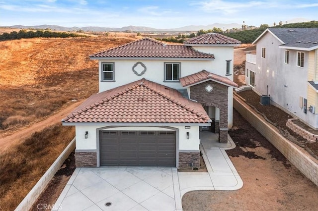 mediterranean / spanish-style house with a mountain view, cooling unit, and a garage