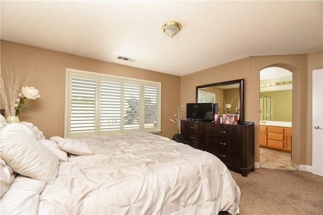 bedroom with light colored carpet and connected bathroom