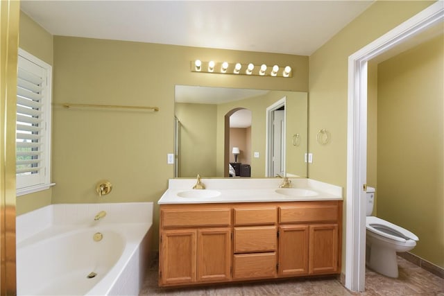 bathroom with vanity, toilet, and tiled tub