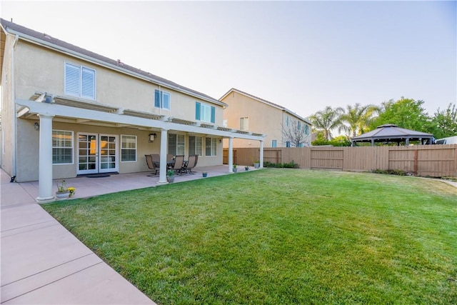 back of property with a pergola, a patio area, and a lawn