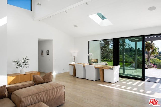 living room with a skylight, beamed ceiling, high vaulted ceiling, and light wood-type flooring