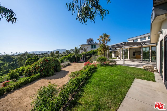 view of yard featuring a mountain view, a pergola, and a patio