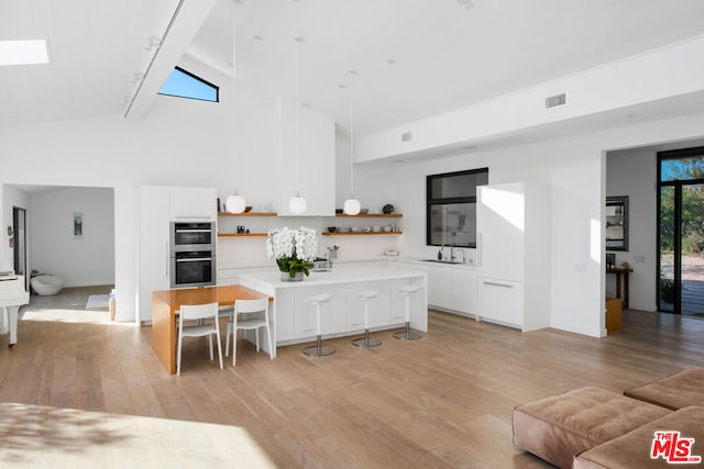 living room with rail lighting, light hardwood / wood-style floors, high vaulted ceiling, and sink