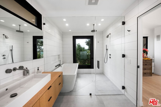 bathroom with wood-type flooring, shower with separate bathtub, and sink