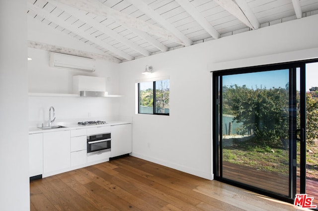 kitchen featuring an AC wall unit, sink, stainless steel appliances, and hardwood / wood-style flooring