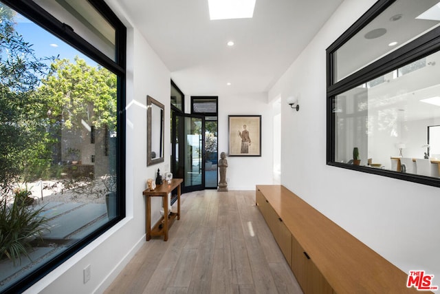 corridor with a skylight and light hardwood / wood-style flooring