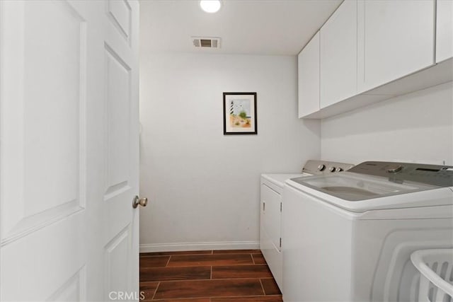 laundry area featuring wood finish floors, visible vents, cabinet space, washing machine and dryer, and baseboards