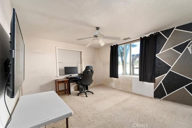 home office featuring carpet, a textured ceiling, visible vents, and a ceiling fan