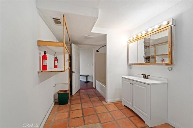 bathroom featuring bathing tub / shower combination, vanity, visible vents, baseboards, and tile patterned floors