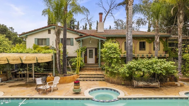 back of house featuring a swimming pool with hot tub and a patio