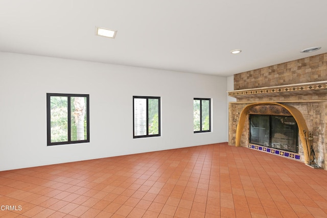 unfurnished living room featuring a fireplace, a wealth of natural light, and tile patterned flooring