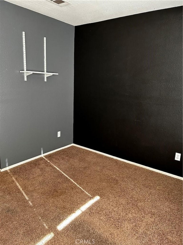 spare room featuring carpet flooring and a textured ceiling