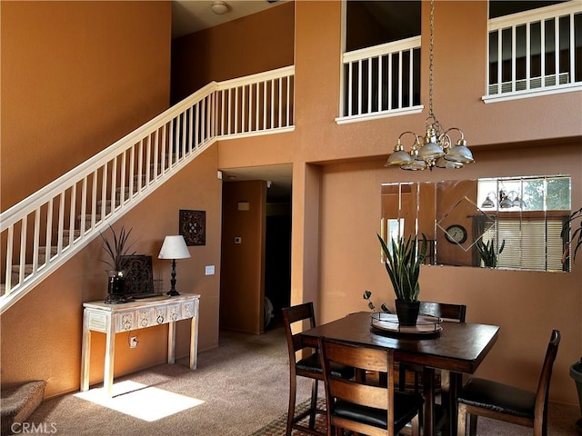 dining space featuring carpet flooring, a high ceiling, and a chandelier