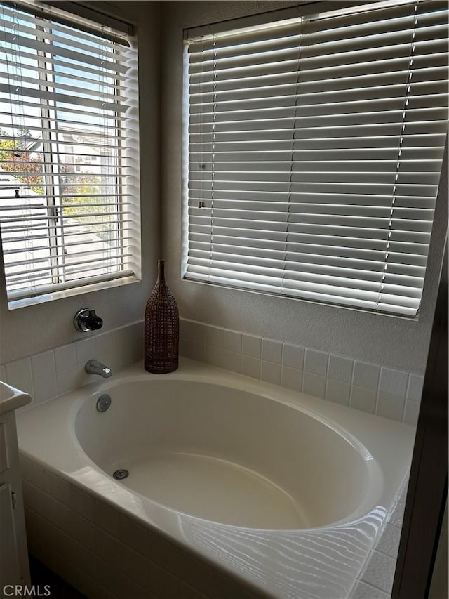 bathroom with tiled bath and vanity