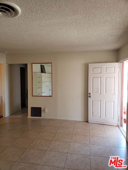 tiled empty room featuring a textured ceiling and plenty of natural light