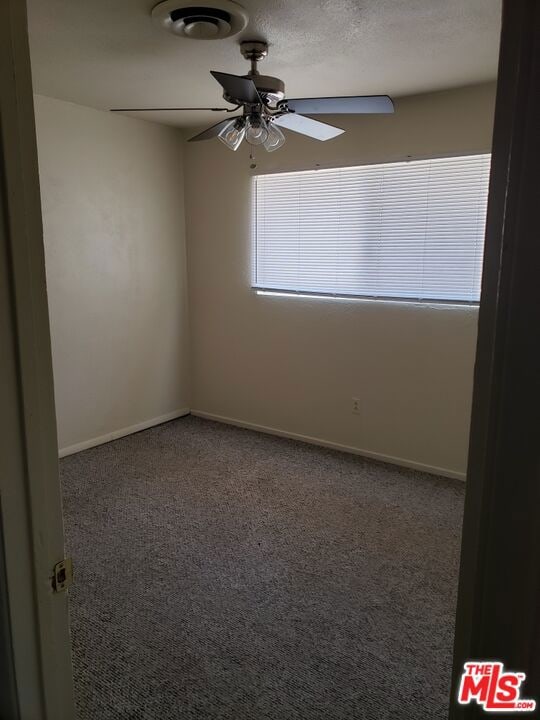 carpeted empty room featuring ceiling fan