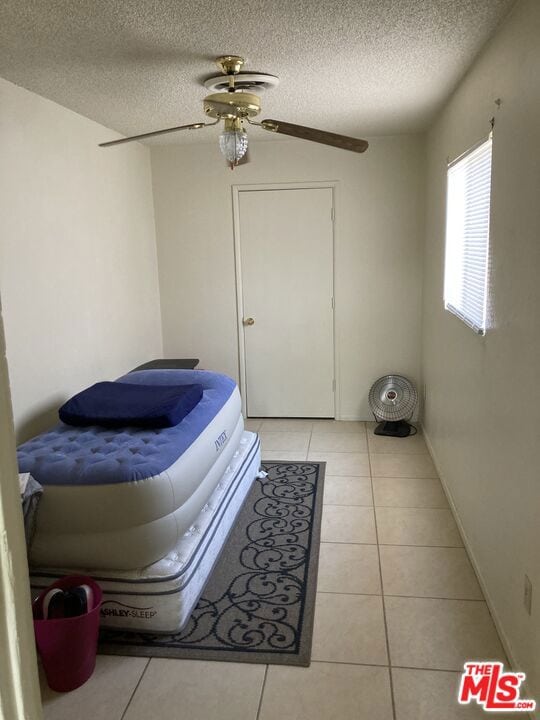 bedroom featuring ceiling fan, a textured ceiling, and light tile patterned flooring