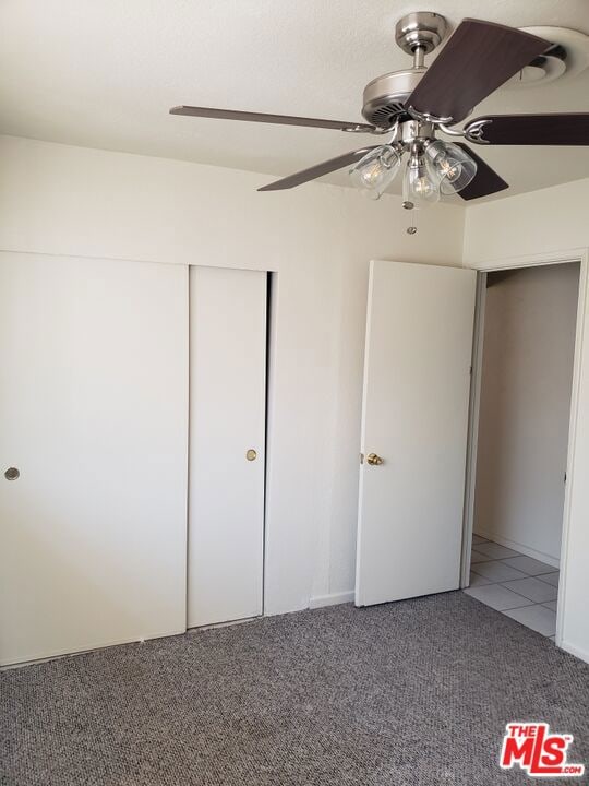 unfurnished bedroom with ceiling fan, carpet floors, and a closet