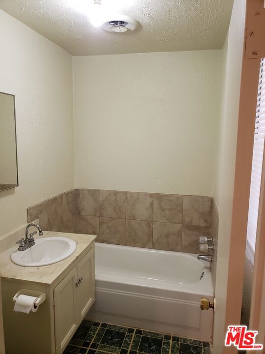 bathroom featuring a bath, vanity, and a textured ceiling