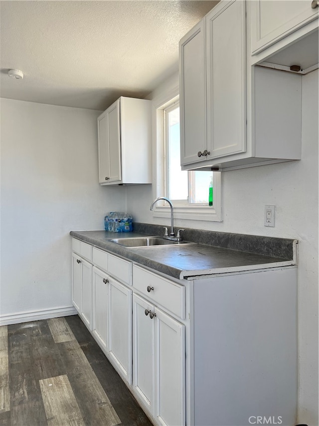 kitchen featuring white cabinets, dark hardwood / wood-style floors, sink, and a textured ceiling