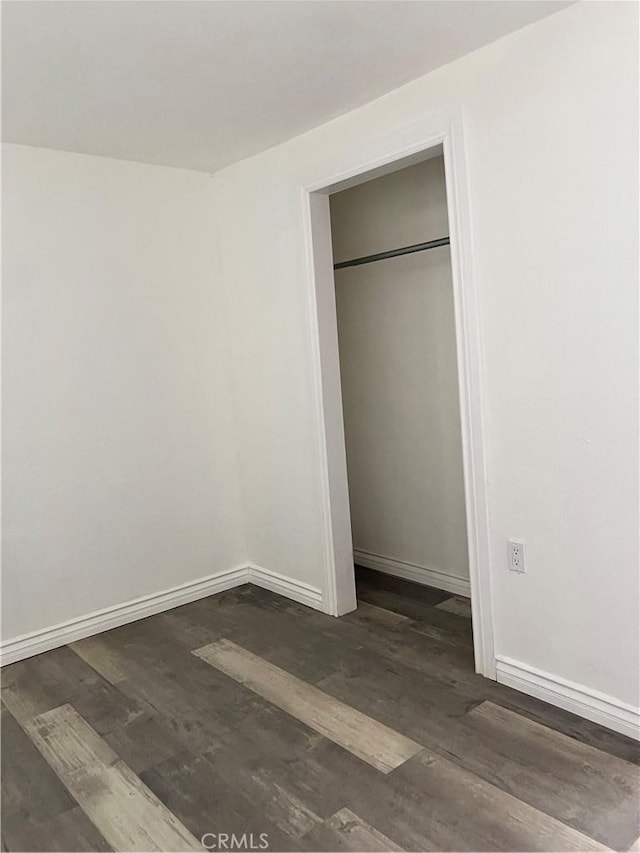 unfurnished bedroom featuring dark wood-type flooring and a closet