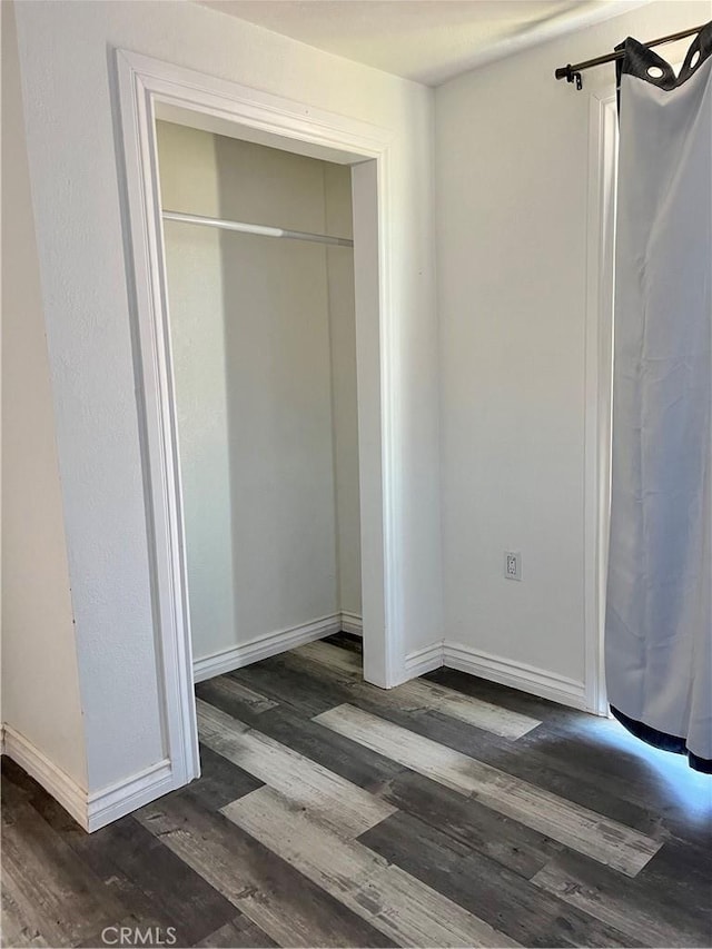 unfurnished bedroom featuring a closet and dark hardwood / wood-style flooring