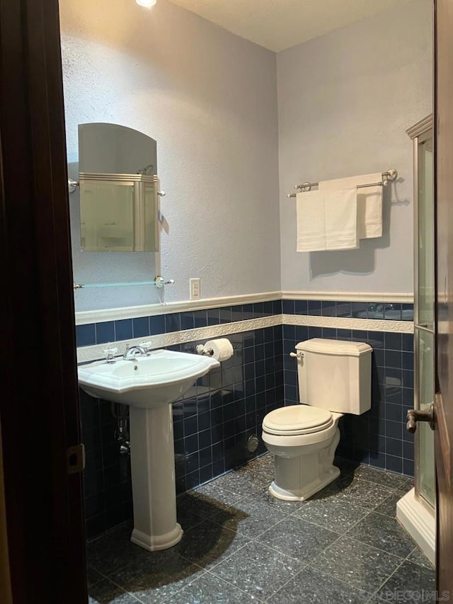 bathroom featuring tile walls, a shower with door, and toilet