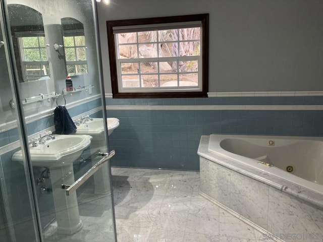 bathroom with tile walls, a wealth of natural light, a washtub, and sink