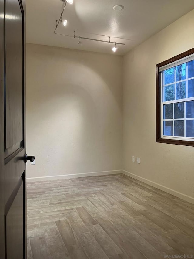 spare room featuring hardwood / wood-style flooring and rail lighting