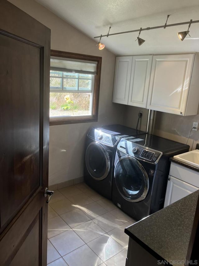 clothes washing area with cabinets, light tile patterned flooring, sink, rail lighting, and separate washer and dryer