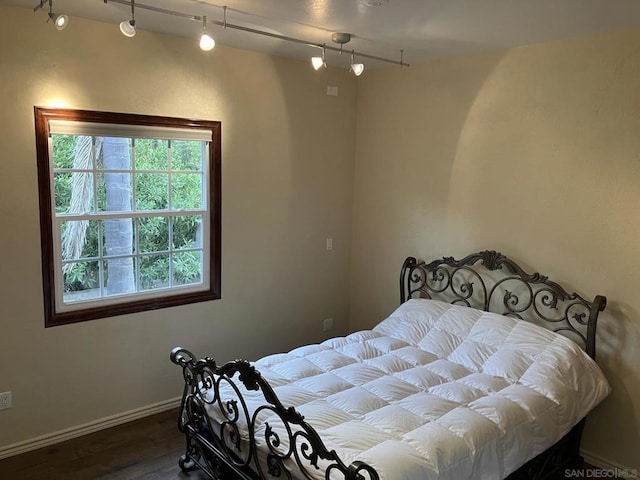 bedroom with rail lighting and hardwood / wood-style floors