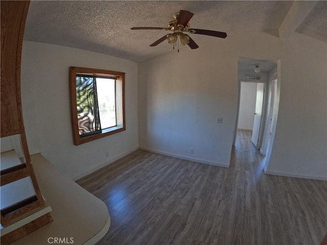 spare room featuring a textured ceiling, dark hardwood / wood-style floors, vaulted ceiling, and ceiling fan