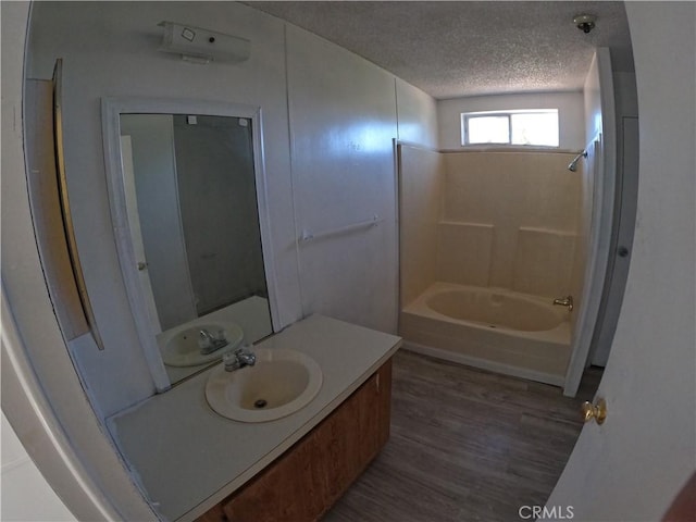 bathroom with hardwood / wood-style flooring, vanity, shower / bath combination, and a textured ceiling