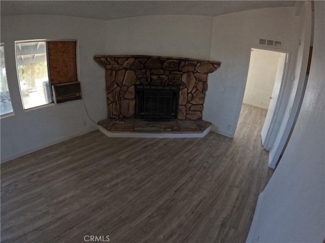 unfurnished living room featuring hardwood / wood-style floors, a stone fireplace, and lofted ceiling