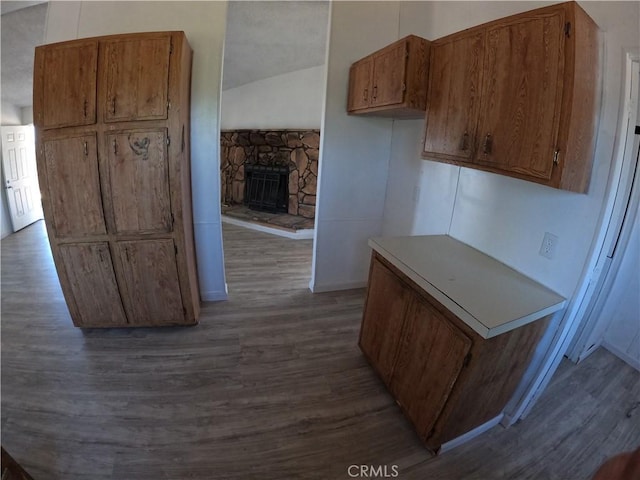 kitchen featuring a fireplace, dark wood-type flooring, and vaulted ceiling