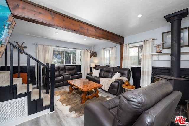 living room featuring beamed ceiling, hardwood / wood-style floors, and a wealth of natural light