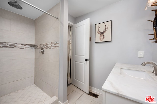 bathroom with a tile shower and vanity