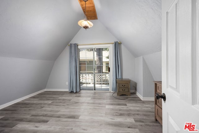 bonus room featuring light wood-type flooring and vaulted ceiling