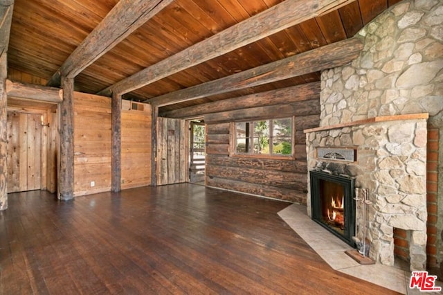 unfurnished living room with dark hardwood / wood-style floors, wood ceiling, a stone fireplace, and beamed ceiling