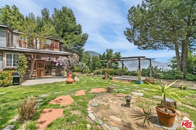 view of yard with a patio area, a pergola, and a mountain view