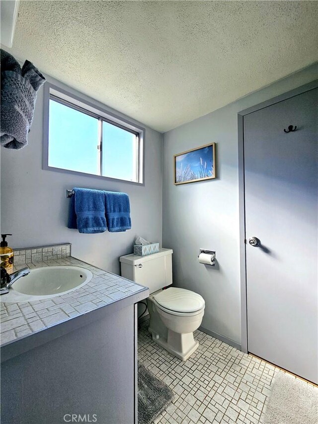 bathroom featuring a textured ceiling, toilet, and vanity