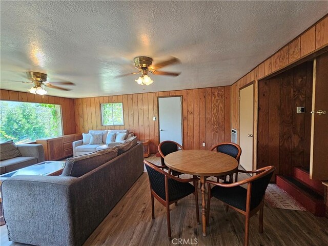 dining room with ceiling fan, dark hardwood / wood-style flooring, and wooden walls